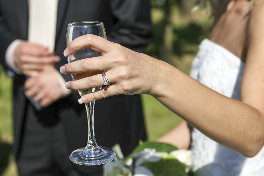 A woman showing off her wedding band holding champagne
