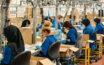 Female workers in a textile factory, sat at sewing machines.