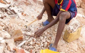 A child breaking up stone with a small pick