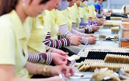 Row of female workers making paintbrushes in a factory