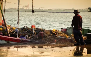 Man with fishing net standing by boat