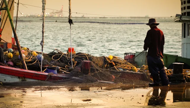 Man with fishing net standing by boat