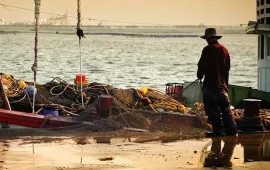 Man with fishing net standing by boat