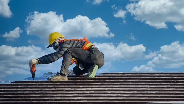 Worker in high-vis jacket and hard hat repairing a roof