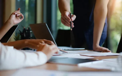 A team of people at a desk working together around a laptop