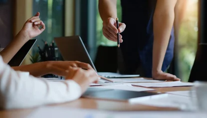 A team of people at a desk working together around a laptop