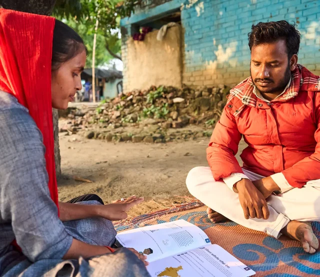 Two people looking at a book of guidance for workers