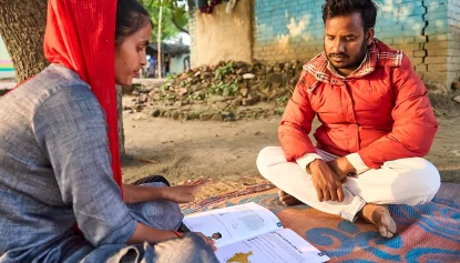 Two people looking at a book of guidance for workers