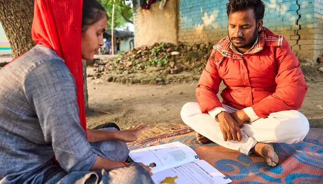 Two people looking at a book of guidance for workers