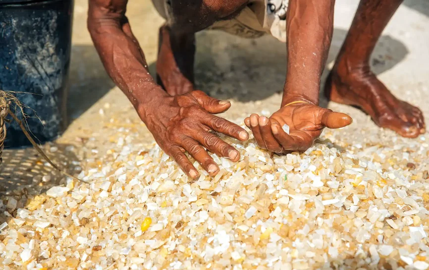 A worker looking through a pile of mined gemstones