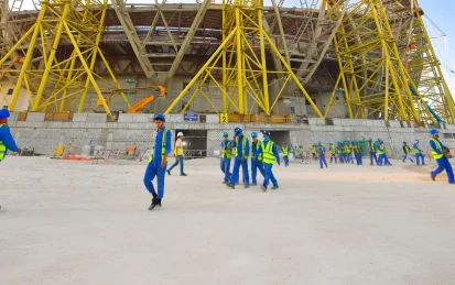 Workers on a construction site of a large stadium building