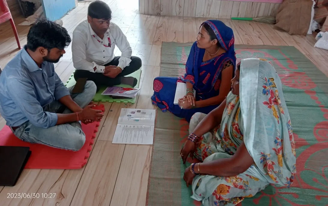 Migrant worker guidance in India: A group of people sat on the floor looking at resources