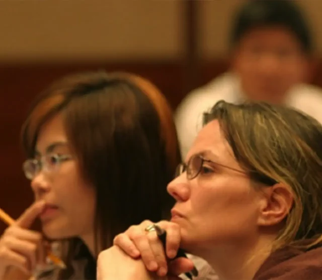 Two women listening to a speaker at an event