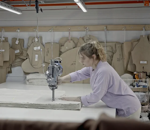 A worker cutting material in a factory